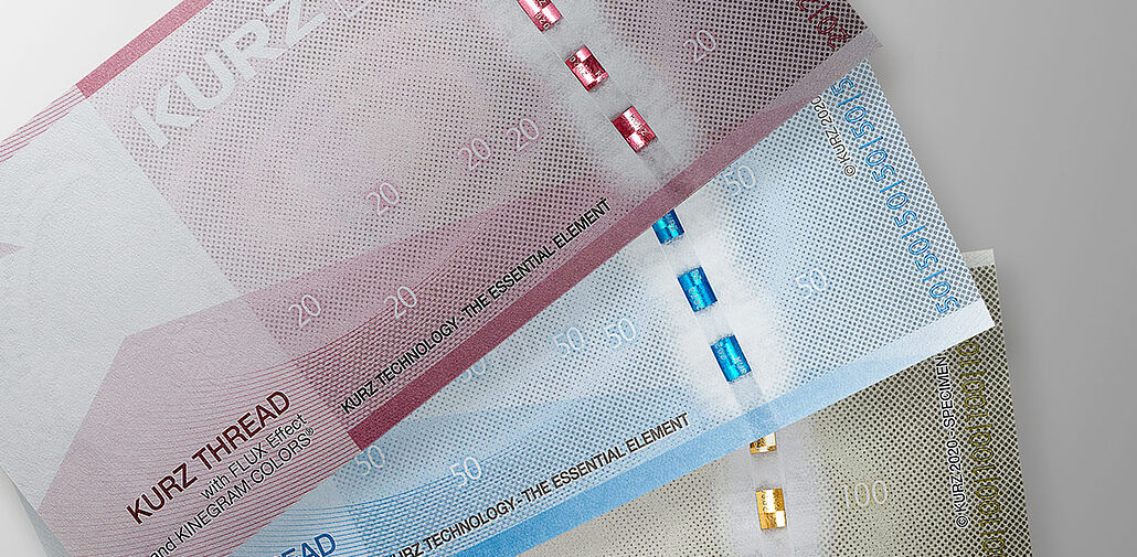 Three sample banknotes with security thread examples in different colors